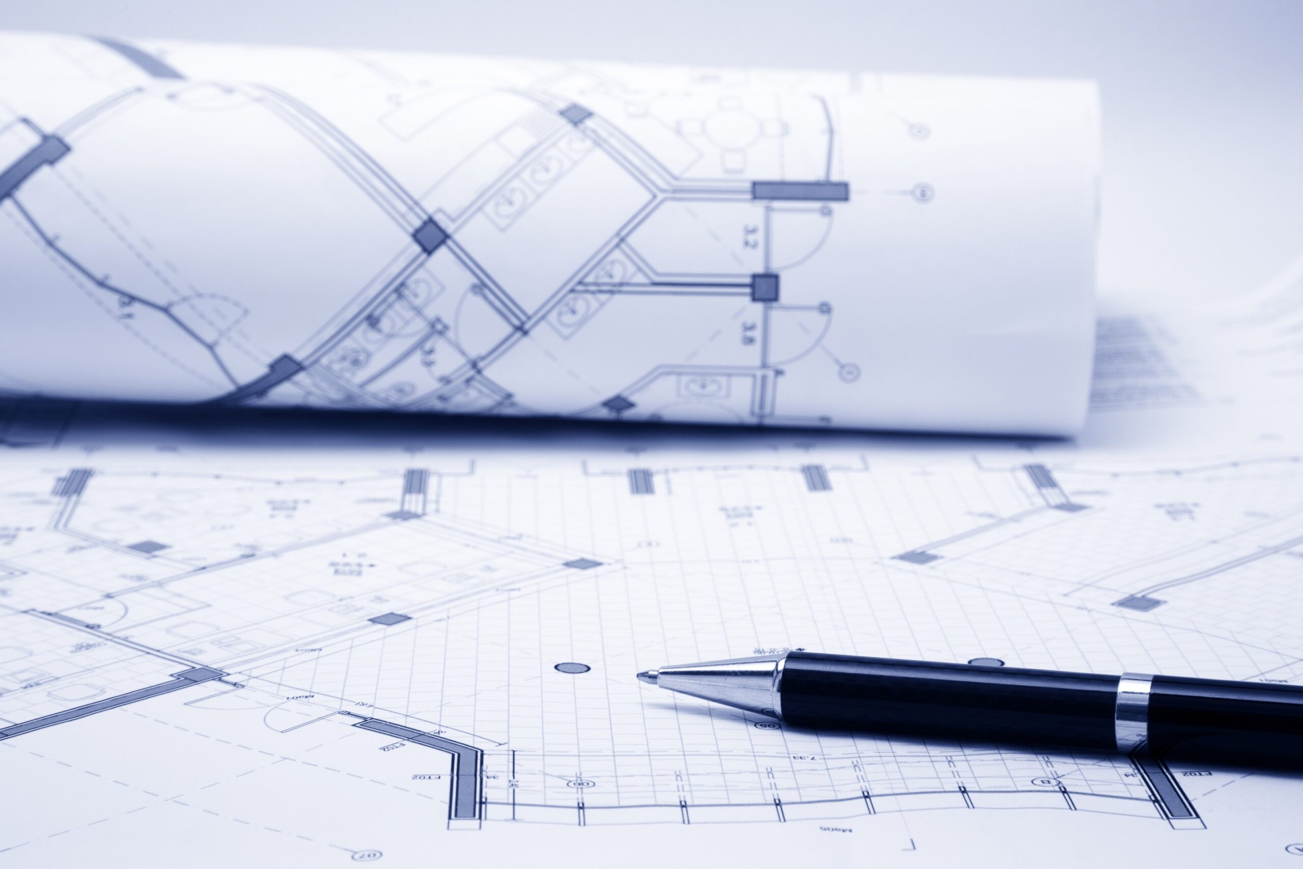 Blueprints and pen on a table.