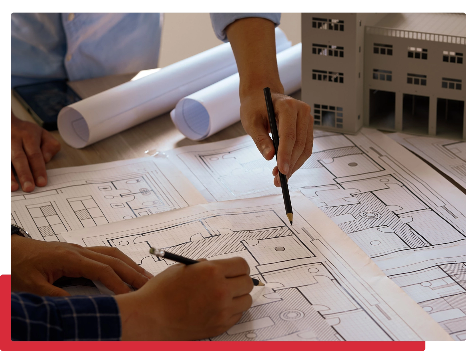 People reviewing architectural blueprints on table.